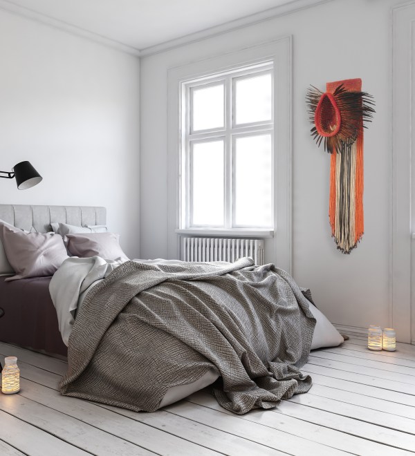 Chambre moderne et minimaliste avec un lit confortable, des coussins, une couverture en désordre, des fenêtres lumineuses, et une décoration murale colorée.